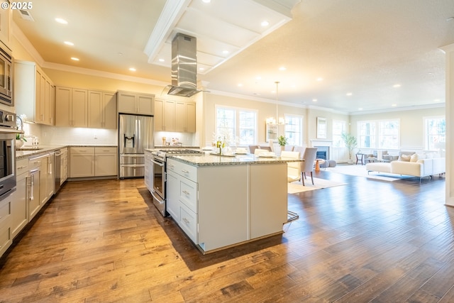 kitchen with appliances with stainless steel finishes, island range hood, wood-type flooring, an island with sink, and a kitchen bar