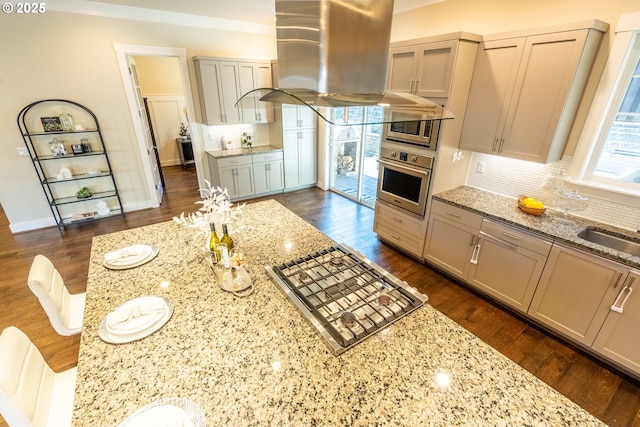 kitchen featuring tasteful backsplash, gray cabinetry, stainless steel appliances, light stone countertops, and dark wood-type flooring