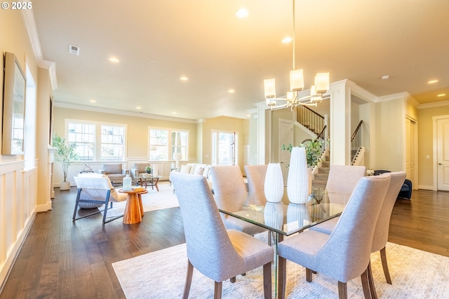 dining space featuring dark wood-type flooring, ornamental molding, an inviting chandelier, and a wealth of natural light