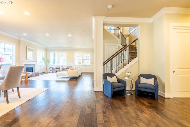 interior space with a tiled fireplace, stairs, dark wood-style flooring, and crown molding