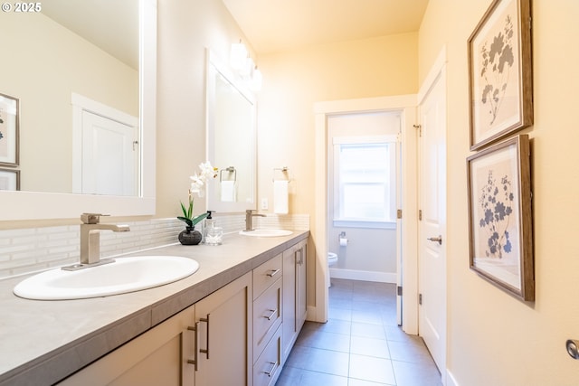 bathroom with a sink, toilet, double vanity, and tile patterned flooring