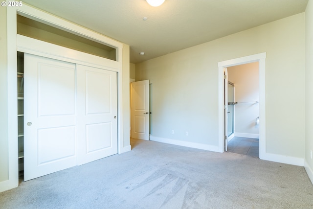 unfurnished bedroom featuring a closet, baseboards, carpet flooring, and ensuite bathroom