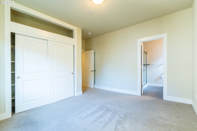 unfurnished bedroom with carpet floors, a closet, and ensuite bathroom