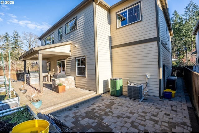 back of house with area for grilling, a patio, a fenced backyard, and central AC
