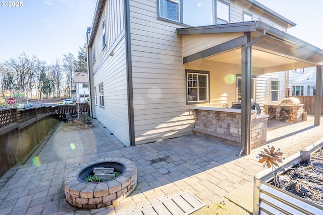 exterior space featuring a fenced backyard, an outdoor kitchen, and an outdoor fire pit
