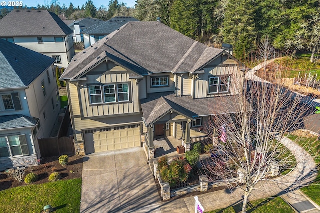 craftsman inspired home featuring concrete driveway, roof with shingles, board and batten siding, a garage, and fence