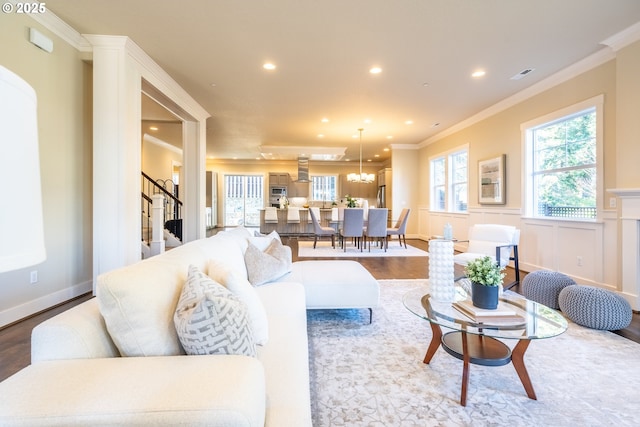 living room with wood-type flooring, an inviting chandelier, and crown molding