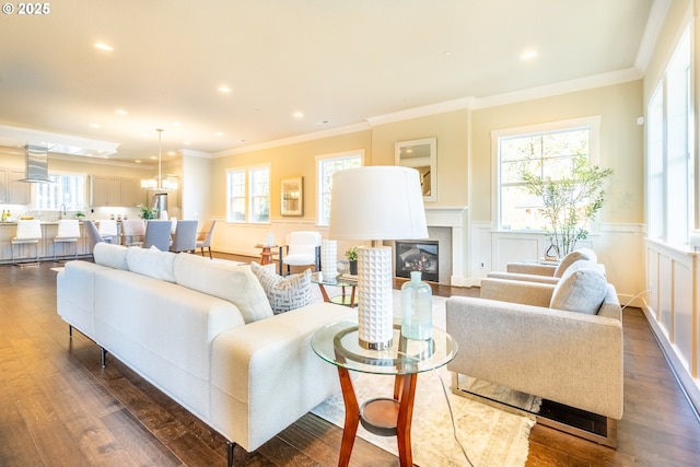 living room with dark wood-style flooring, a wainscoted wall, plenty of natural light, and a glass covered fireplace