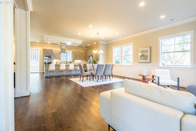 living area featuring crown molding, a wainscoted wall, a chandelier, recessed lighting, and dark wood-style flooring