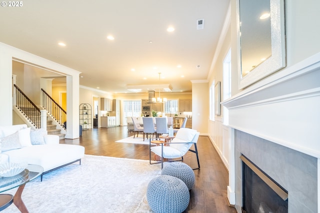 living area with visible vents, dark wood-style flooring, a fireplace, crown molding, and stairs