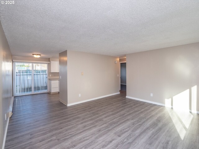 7450 N Portsmouth Ave, Portland, OR 97203 - unfurnished living room with a textured ceiling, baseboards, and dark wood-style flooring