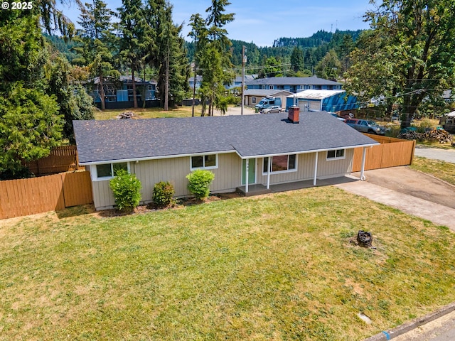 ranch-style home with fence, a front lawn, and roof with shingles