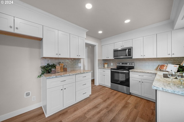 kitchen featuring crown molding, stainless steel appliances, tasteful backsplash, light wood-style flooring, and baseboards