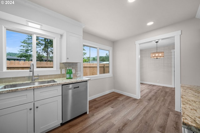 kitchen with tasteful backsplash, light wood-style flooring, stainless steel dishwasher, white cabinetry, and a sink