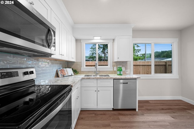 kitchen featuring decorative backsplash, appliances with stainless steel finishes, a sink, wood finished floors, and baseboards