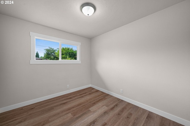 spare room featuring baseboards and wood finished floors