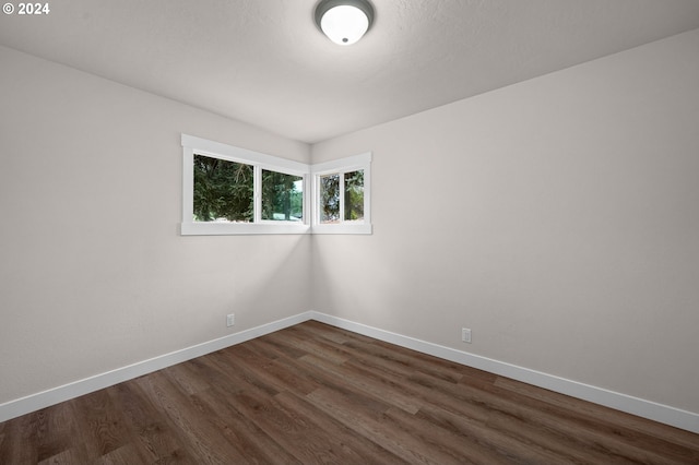 empty room with dark wood finished floors and baseboards