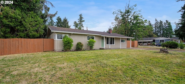 ranch-style house with fence, a chimney, and a front lawn