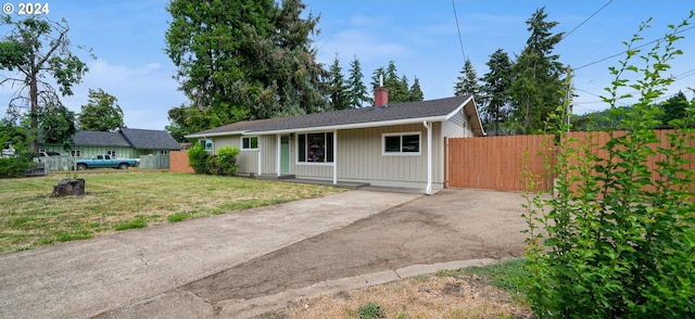 ranch-style home with driveway, fence, a chimney, and a front lawn