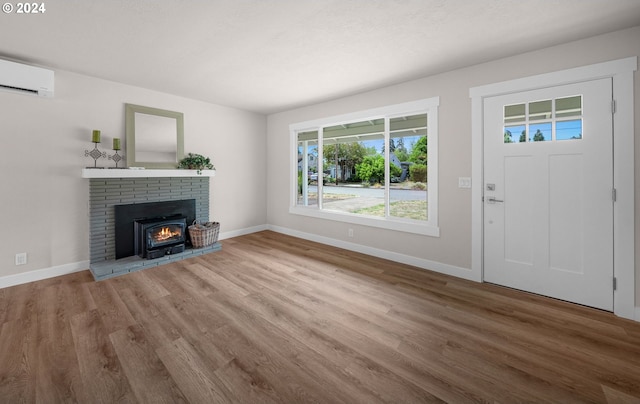 unfurnished living room with a wall mounted air conditioner, wood finished floors, and baseboards