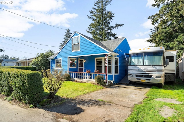 bungalow featuring a front yard, covered porch, and roof with shingles