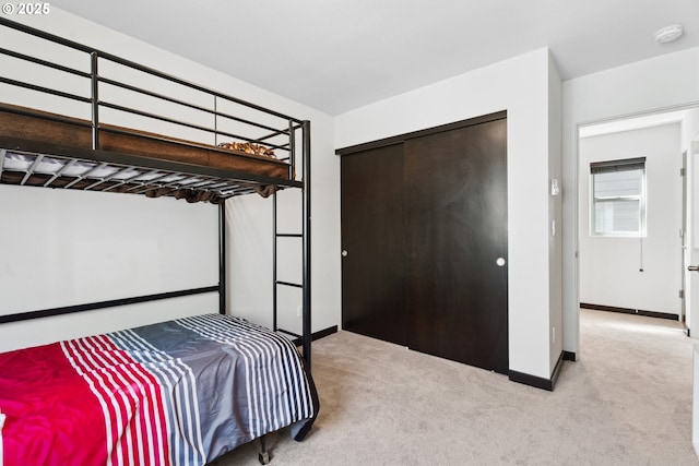 carpeted bedroom with baseboards and a closet