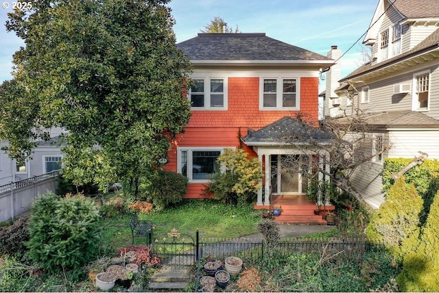 view of front of house featuring a shingled roof and fence private yard