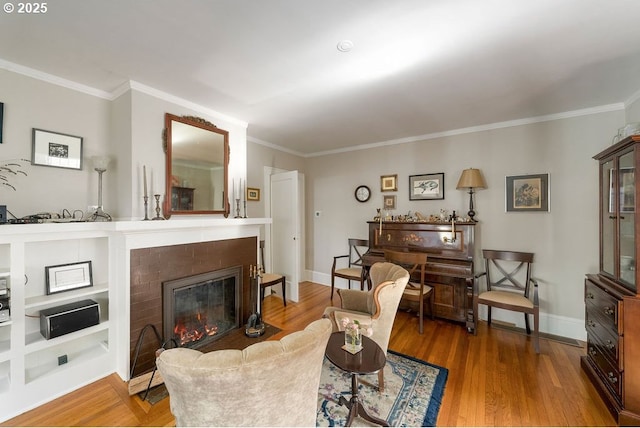 living room with a fireplace with flush hearth, crown molding, baseboards, and wood finished floors