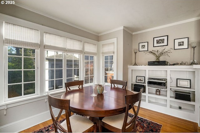 dining space featuring ornamental molding, wood finished floors, and baseboards