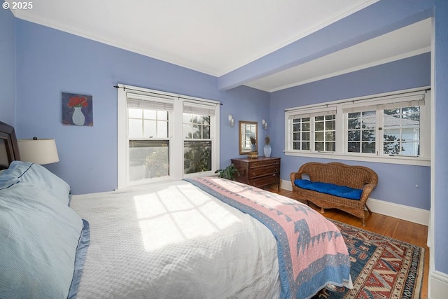 bedroom with beam ceiling, crown molding, baseboards, and wood finished floors