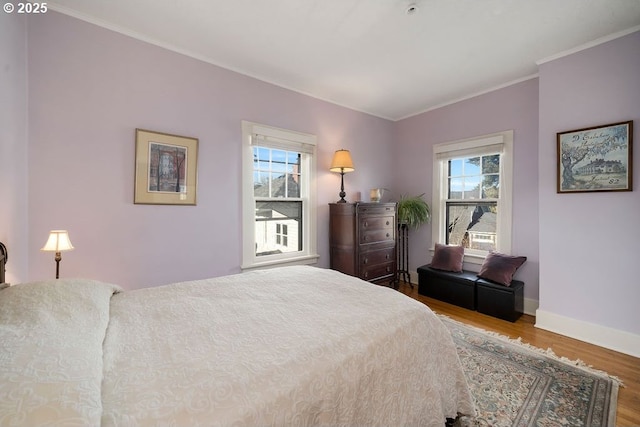 bedroom with multiple windows, baseboards, wood finished floors, and ornamental molding