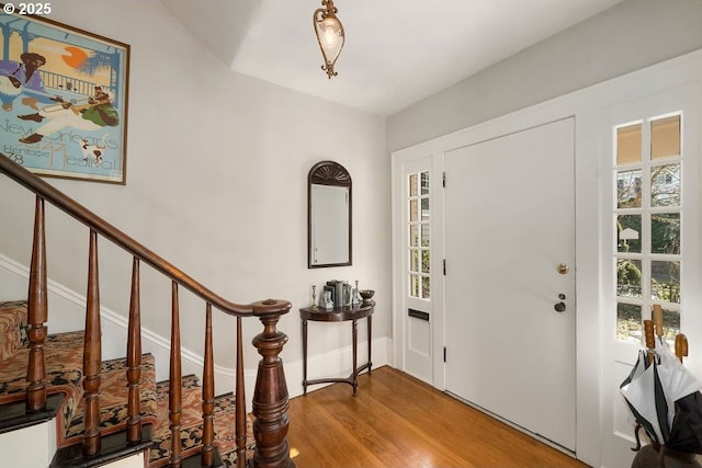 foyer with a wealth of natural light, stairway, baseboards, and wood finished floors