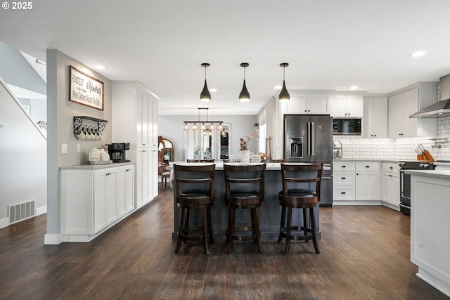 kitchen featuring dark wood-style floors, visible vents, appliances with stainless steel finishes, and backsplash