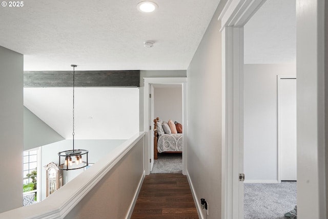 hall with baseboards, dark wood-style flooring, and a textured ceiling