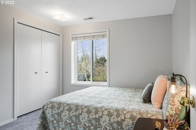 carpeted bedroom featuring a textured ceiling, visible vents, and a closet