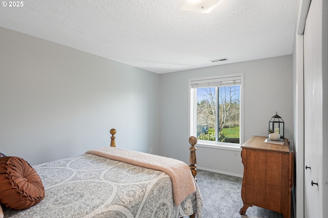 bedroom featuring carpet floors, visible vents, a textured ceiling, and baseboards