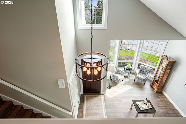 foyer with stairs, wood finished floors, plenty of natural light, and lofted ceiling