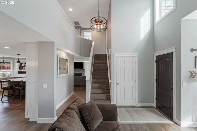 entrance foyer with baseboards, stairs, visible vents, and wood finished floors