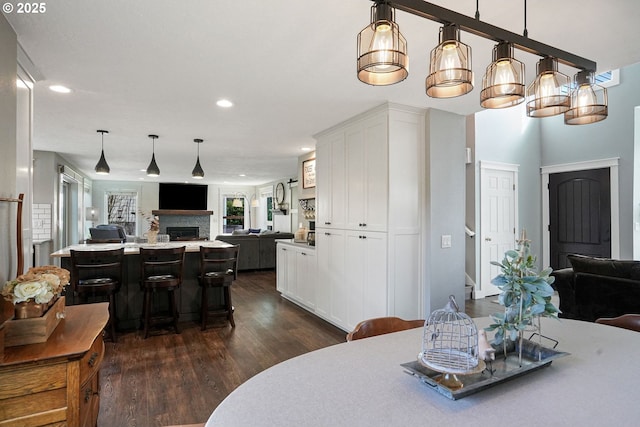 dining space featuring recessed lighting, a fireplace, and dark wood finished floors