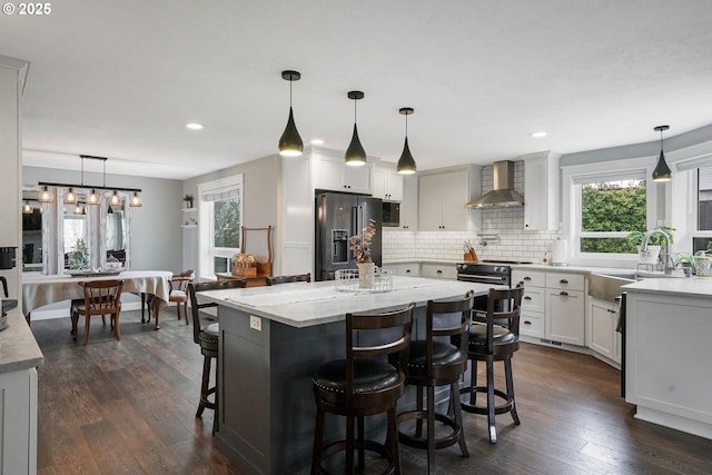 kitchen with dark wood-type flooring, a sink, wall chimney exhaust hood, decorative backsplash, and black appliances