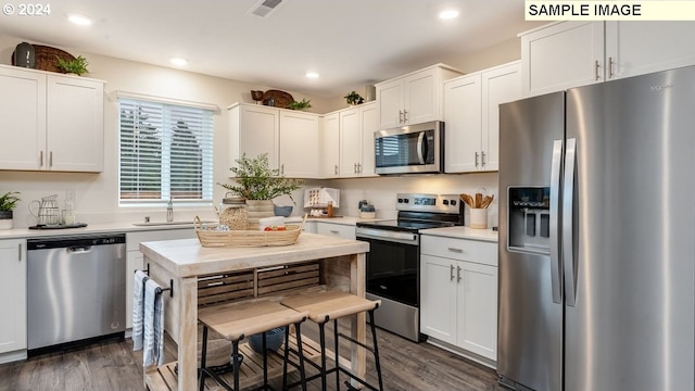 kitchen with appliances with stainless steel finishes, a sink, dark wood-style floors, and visible vents
