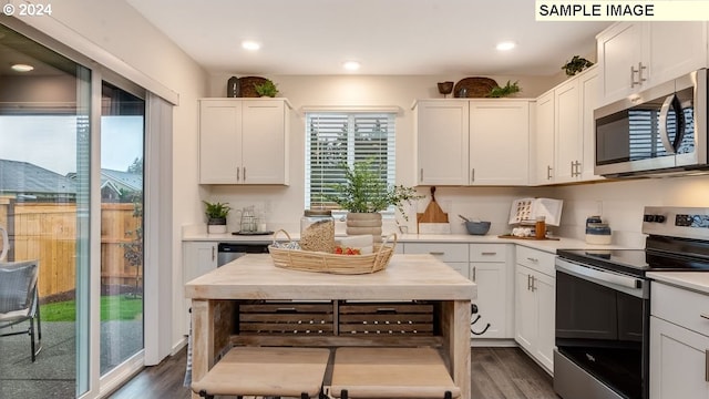 kitchen featuring white cabinets, stainless steel appliances, light countertops, and dark wood-type flooring