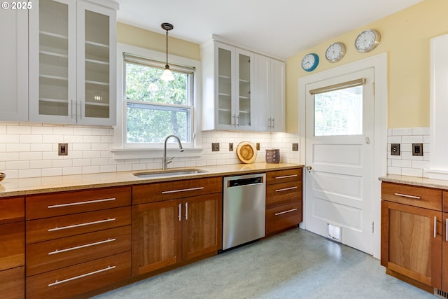 7154 N Greeley Ave, Portland, OR 97217 - kitchen with stainless steel dishwasher, a sink, brown cabinetry, and light stone counters