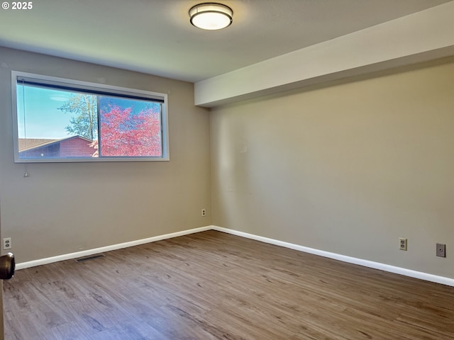 empty room with baseboards, wood finished floors, and visible vents
