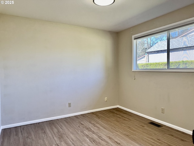 spare room with baseboards, wood finished floors, and visible vents