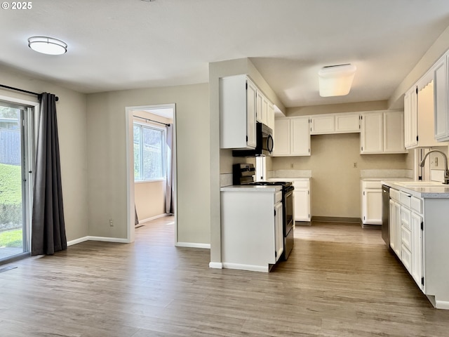 kitchen with light countertops, baseboards, stainless steel appliances, and a sink