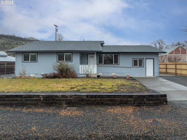 view of front of house with roof with shingles, fence, and a front lawn