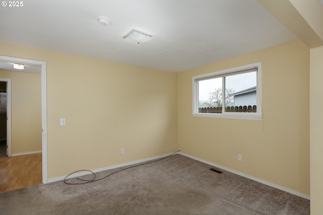 carpeted spare room featuring visible vents and baseboards