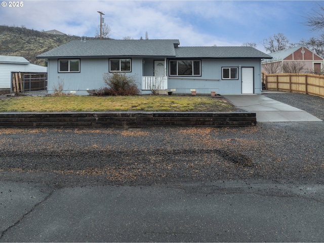 single story home with a garage, concrete driveway, and fence