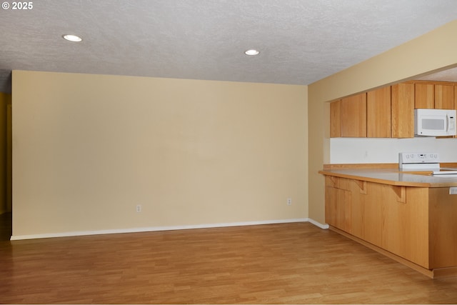 kitchen with light countertops, light wood-style floors, white appliances, a peninsula, and baseboards